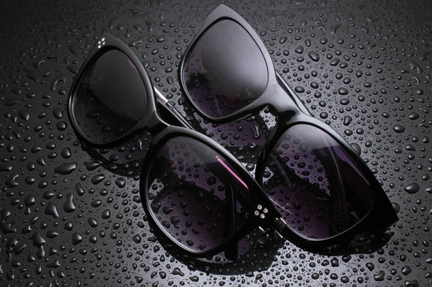 due paia di occhiali da sole con gocce d'acqua su fondo nero
 - Foto, immagini