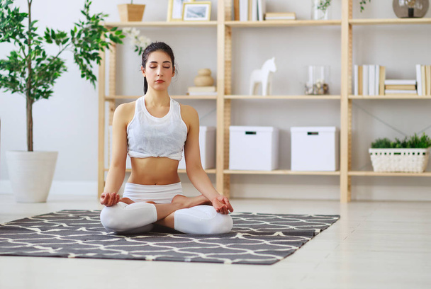 woman doing yoga, meditating in Lotus position at home     - Фото, изображение