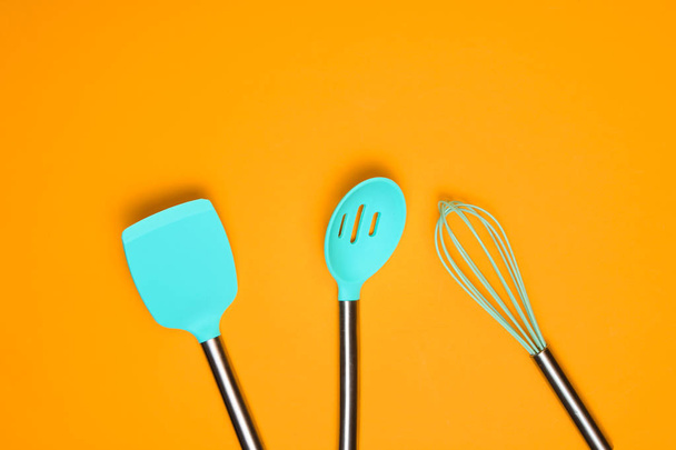 Set of tools for cooking on yellow background. Silicone paddles with metal handles, whisk. Top view. Copy spac - 写真・画像