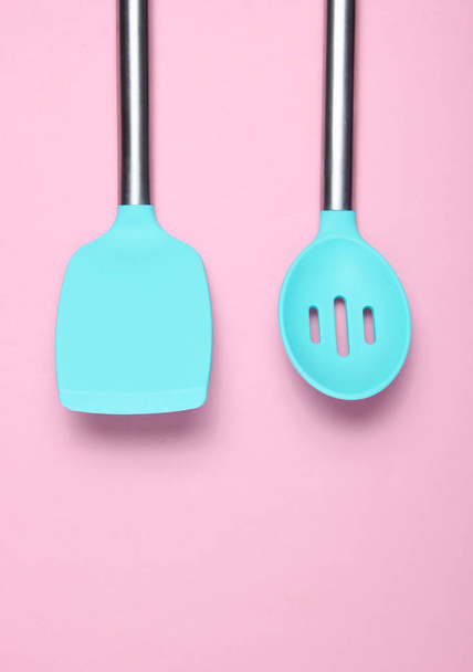 Werkzeuge zum Kochen auf rosa Hintergrund. Silikon-Paddel mit Metallgriffen. Ansicht von oben. Kopierraum - Foto, Bild