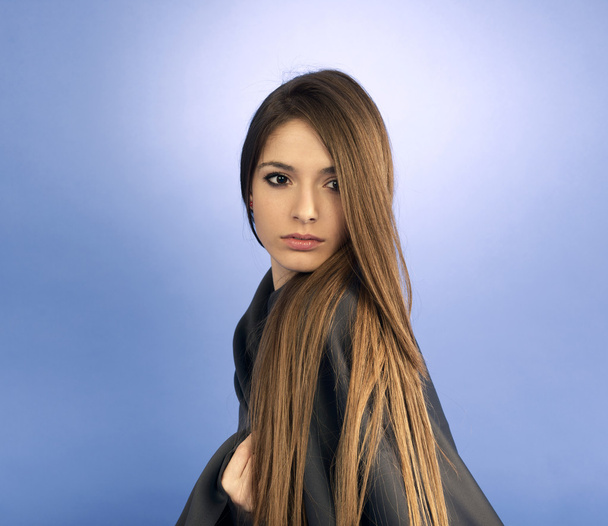 Portrait of a young woman standing against a blue background - Photo, Image