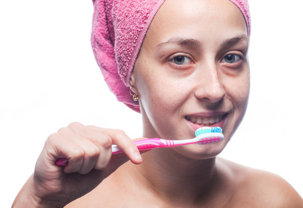 Piękna kobieta szczotkowanie zębów z ręcznikiem na głowie. Poranne leczenie - Zdjęcie, obraz