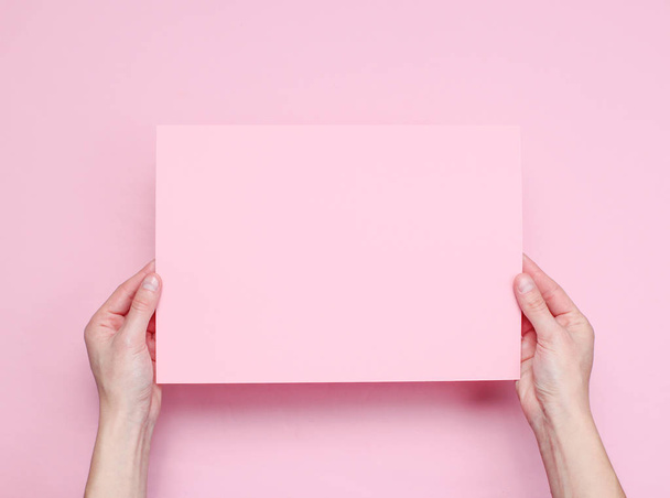 Mains féminines tenant feuille de papier rose sur fond rose. Vue de dessus. Maquette, espace de copie, minimalisme
 - Photo, image