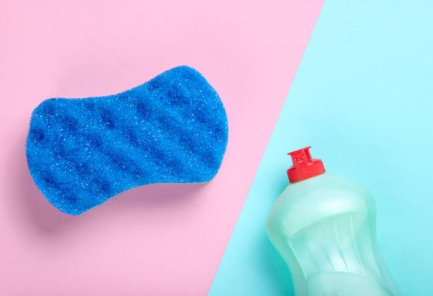 Detergent bottle and sponge on blue pink pastel background. Top view, minimalism - Fotó, kép