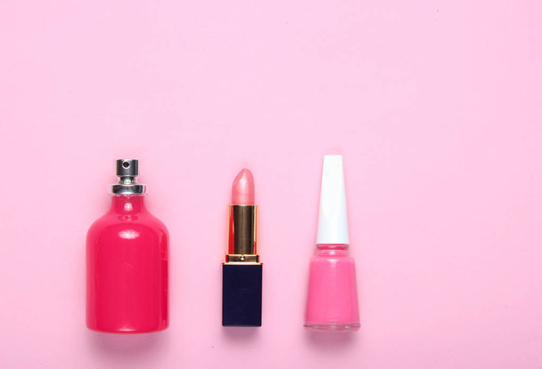 香水瓶、口紅、ピンクの背景にピンクのマニキュア。トップビュー、ミニマリズム - 写真・画像