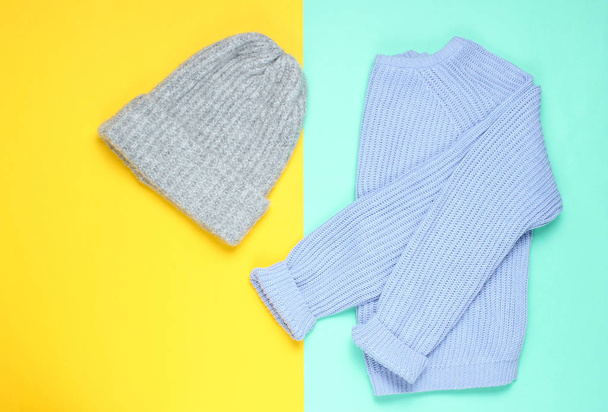 Sombrero de lana de invierno, suéter sobre un fondo de papel de colores, minimalismo, vista superior, estilo plano
 - Foto, Imagen