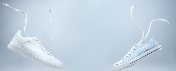 Білі кросівки і плаваючі мережива на сірому фоні, мінімалізм
 - Фото, зображення