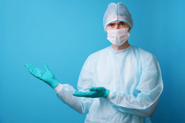 Хирург в стерильной синей форме, медицинских перчатках и маске
 - Фото, изображение