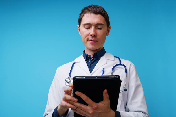 Πορτρέτο του γιατρού με στηθοσκόπιο και tablet υπολογιστή στο χέρι σε μπλε φόντο - Φωτογραφία, εικόνα