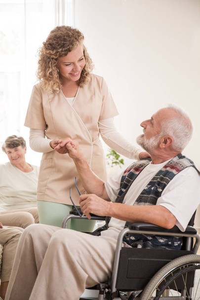Senior man on wheelchair with helpful nurse holding his hand - Fotografie, Obrázek