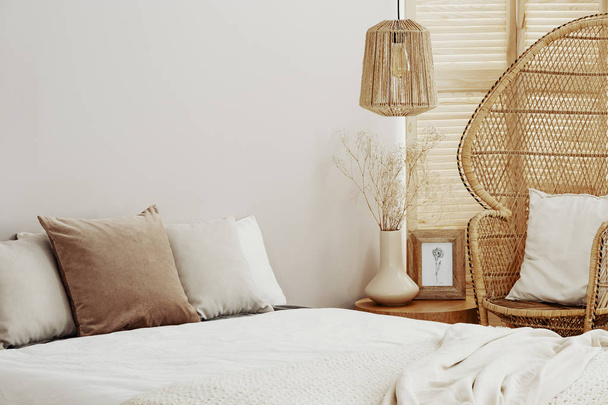 Белый и яркий интерьер спальни с плетеным стулом павлина и ротанговой лампой
 - Фото, изображение