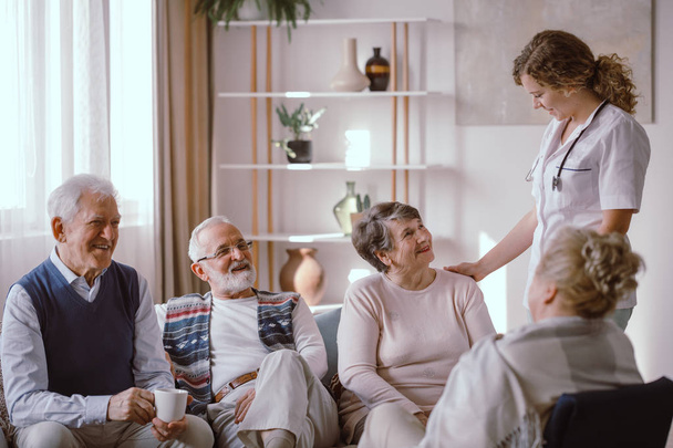 Smiling seniors talking with nurse in the retirement home - Foto, Imagem