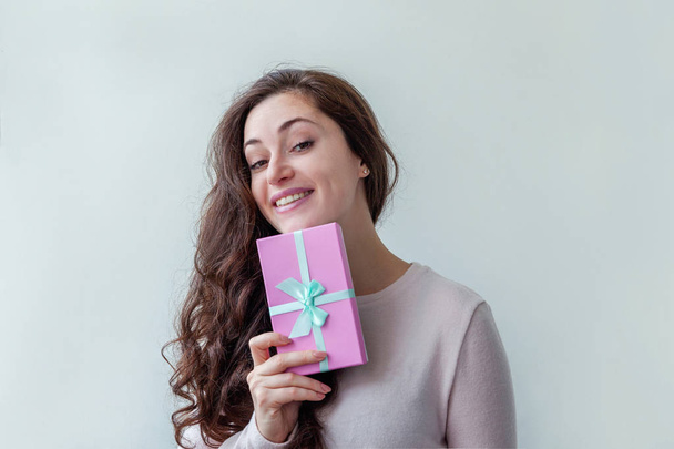 Young positive woman holding small pink gift box isolated on white background. Preparation for holiday. Girl looking happy and excited - Fotografie, Obrázek
