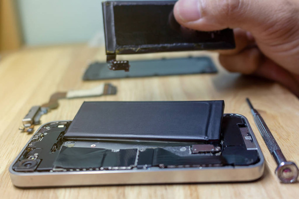 Iphone repairs install battery into the motherboard for smartphone By technician on desk - Фото, изображение