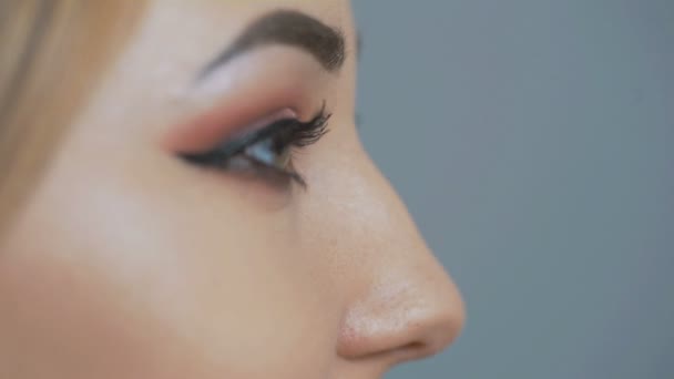 część kobiecego profilu twarzy, pewny wygląd pięknej dziewczyny z makijażem na tle Studio, koncepcja kosmetyków i urody - Materiał filmowy, wideo
