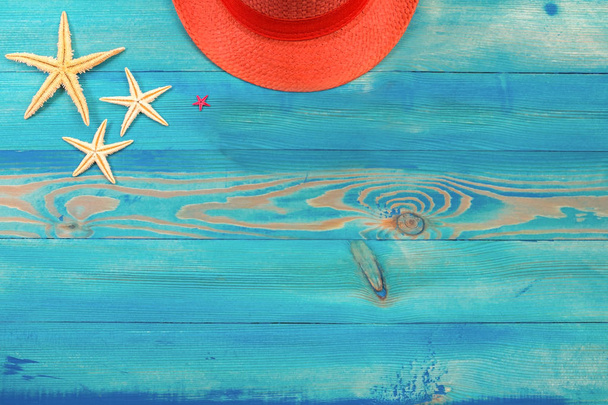 Top view on living coral color hat and starfish on blue painted vintage wooden texture. Flat lay, copy space. - Photo, Image