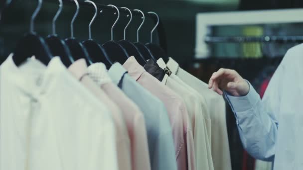 Nahaufnahme einer Frau berührt Kleiderbügel mit Blusen im Showroom - Filmmaterial, Video