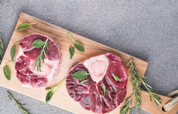 Sliced meat on a wooden board with herbs and spices. Raw meat on - Photo, Image