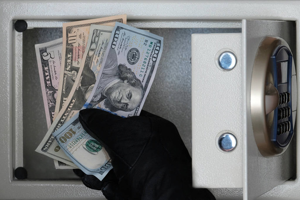 Een ' Black-gloved Thief ' opent de veilige deur met een combinatieslot. Veiligheid thuis, Hotel en kantoor. Diefstal van kostbaarheden en geld. - Foto, afbeelding