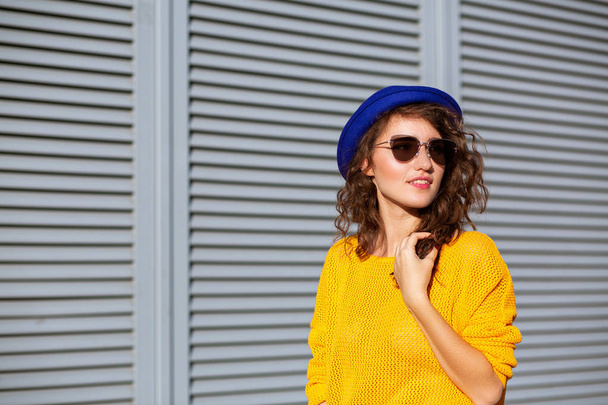Уличный портрет милой девушки в синей шляпе и желтом трикотаже
 - Фото, изображение