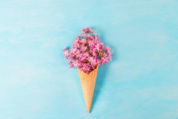 cone de sorvete com flores de primavera rosa cereja ou sakura flores no fundo azul. Conceito de mola mínima. Depósito plano
 - Foto, Imagem