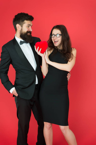 Couple in love dating anniversary. Man tuxedo and girl hold hear soft toy romantic anniversary. Valentines day holiday. Do not play with my heart. Man with beard and woman happy celebrate anniversary - Photo, Image