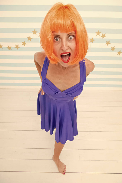 Girl bob wig posing striped background of studio. Create your own mood. Lady red or ginger wig posing in blue dress. Comic and humorous concept. Woman playful mood having fun. Fun and entertainment - Foto, Imagen