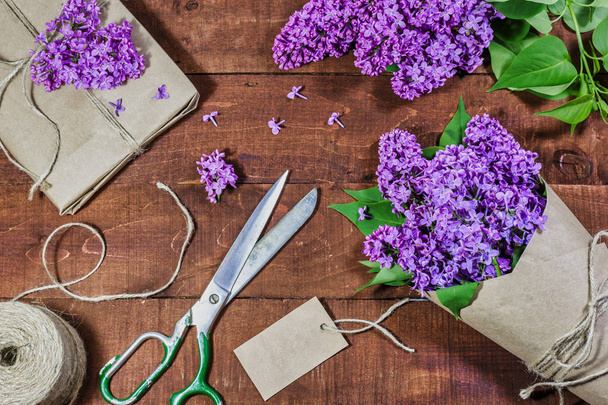 Gift and bouquet of lilacs on a wooden table - Фото, зображення