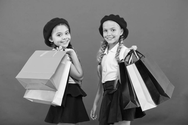 Shopping become fun with best friends. Kids cute schoolgirls hold bunch shopping bags. Children satisfied by shopping red background. Obsessed with shopping and clothing malls. Shopaholic concept - Photo, Image