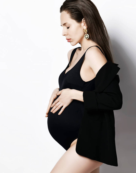 Pregnancy, maternity, preparation and expectation concept. Beautiful fashion pregnant woman holds hands on belly  - Fotó, kép