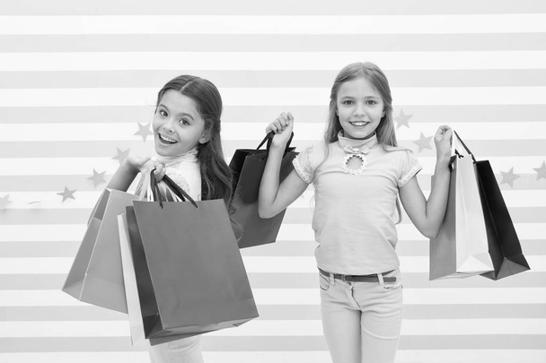 Children satisfied shopping striped background. Obsessed with shopping and clothing malls. Discount concept. Kids cute girls hold shopping bags. Shopping discount season. Spending great time together - Foto, Bild