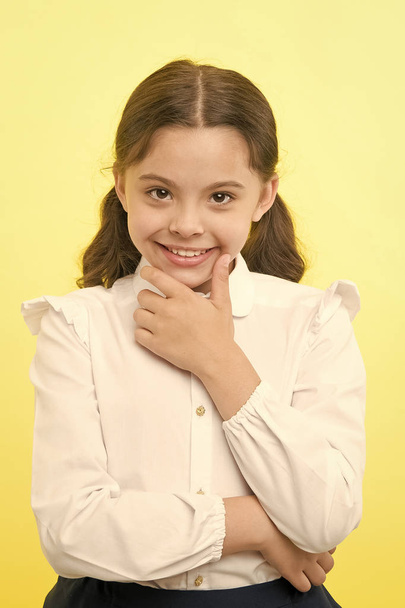 She is planning a prank. Girl school uniform smiling cunning face yellow background. Girl happy back to school. Child ready back to school end continue fun. Schoolgirl formal outfit looks cute - Fotó, kép
