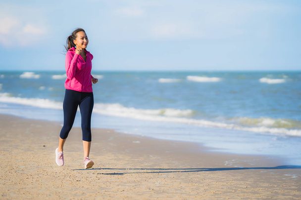 Portrétní krásná mladá asijská žena běžící nebo cvičená na tropicské přírodní krajině plážového mořského oceánu pro zdravý koncept - Fotografie, Obrázek
