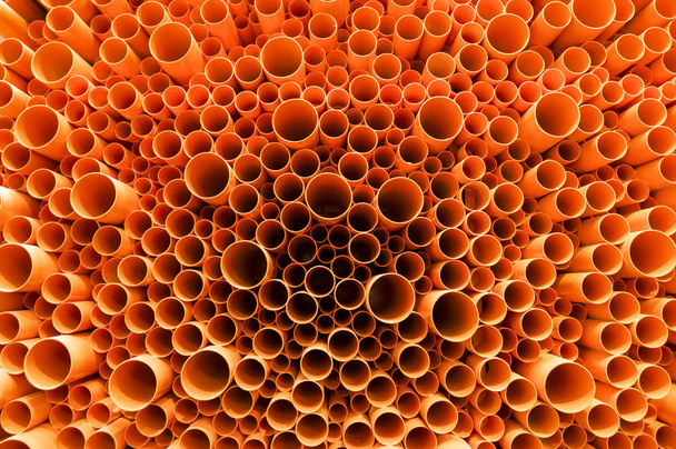 Tubi in PVC arancione impilati in cantiere
 - Foto, immagini