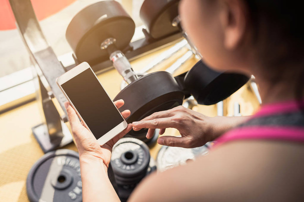 Young asian woman using smartphone in gym - Foto, Imagem