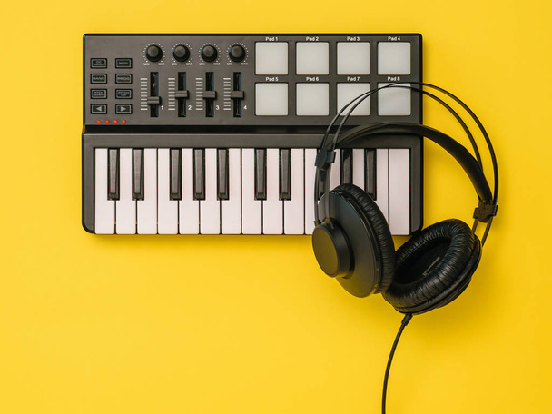 Music mixer and black headphones on yellow background. The view from the top. - Photo, Image