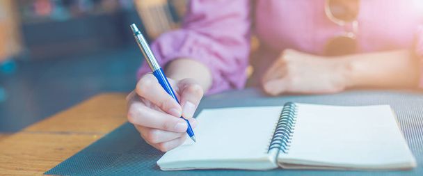 Woman hand is writing on a notepad with a pen.Web banner. - Foto, imagen