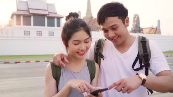 Slow Motion-reiziger Aziatische paar richting op locatie kaart in Bangkok, Thailand, lieve paar met behulp van mobiele telefoon op zoek kaart terwijl het doorbrengen van vakantie reis in zonsondergang. Lifestyle paar reizen concept. - Video