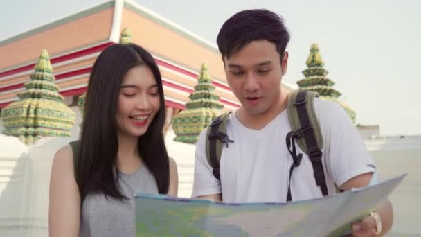 Traveler Asian couple direction on location map in Bangkok, Thailand, sweet Asia couple looking on map find landmark while spending holiday trip. Lifestyle couple travel in city concept. - Footage, Video