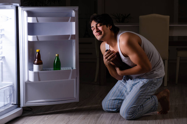 冷蔵庫の近くで夜に食事を壊す男 - 写真・画像