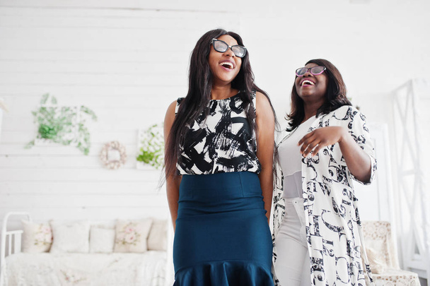 Two african woman friends wear on eyeglasses posed indoor white  - Foto, afbeelding