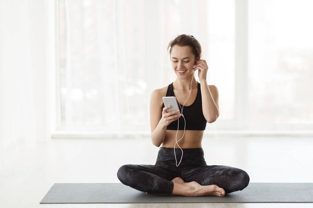 Donna dopo aver praticato yoga, Rilassarsi con lo smartphone
 - Foto, immagini