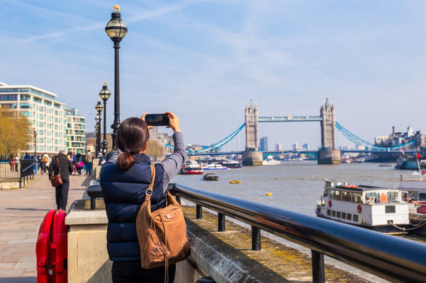 Tower Bridge 'de cep telefonu kamerasıyla fotoğraf çeken bir kadın turist.. - Fotoğraf, Görsel