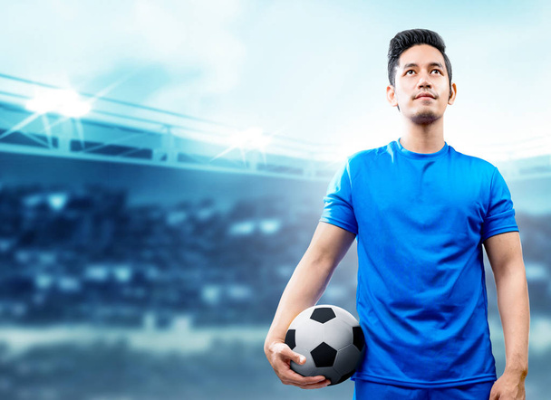 Asian football player man in blue jersey holding the ball on the - Valokuva, kuva