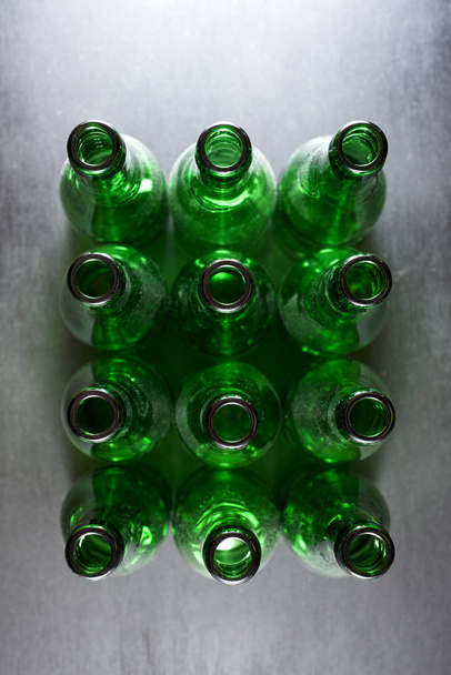 Green bottles of beer on a metal table - Фото, изображение