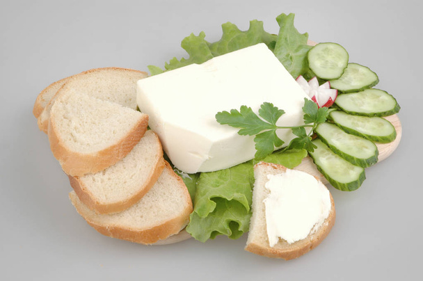 Świeży chleb z masłem, sałata, rzodkiewka, ogórek i pietruszka na pokładzie na szarym białym tle - Zdjęcie, obraz