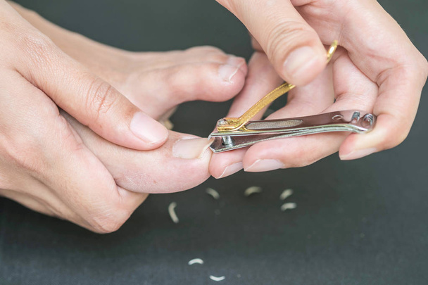 Woman cutting toenail with nail scissors - Photo, Image
