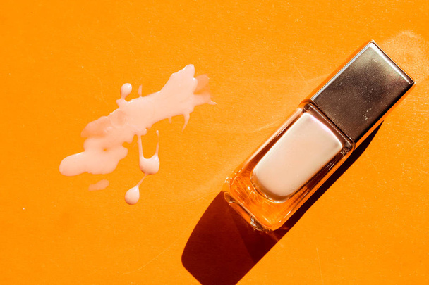 Drops of nail polish and glass jar on orange background. - Фото, изображение