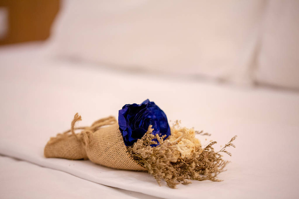 γαμήλια κουμπότρυπα με μπλε και στεγνά λουλούδια σε λεηλασία στο κρεβάτι - Φωτογραφία, εικόνα