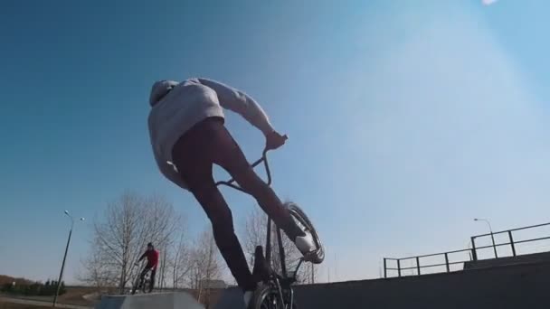 Jeździec BMX jeżdżący na rampach i wykonujący triki w skateparku - Materiał filmowy, wideo